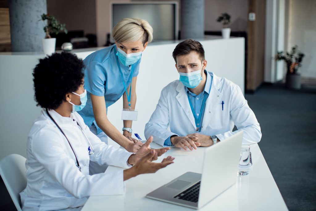 grupo expertos medicos hablando mientras usa computadora portatil reunion hospital 1
